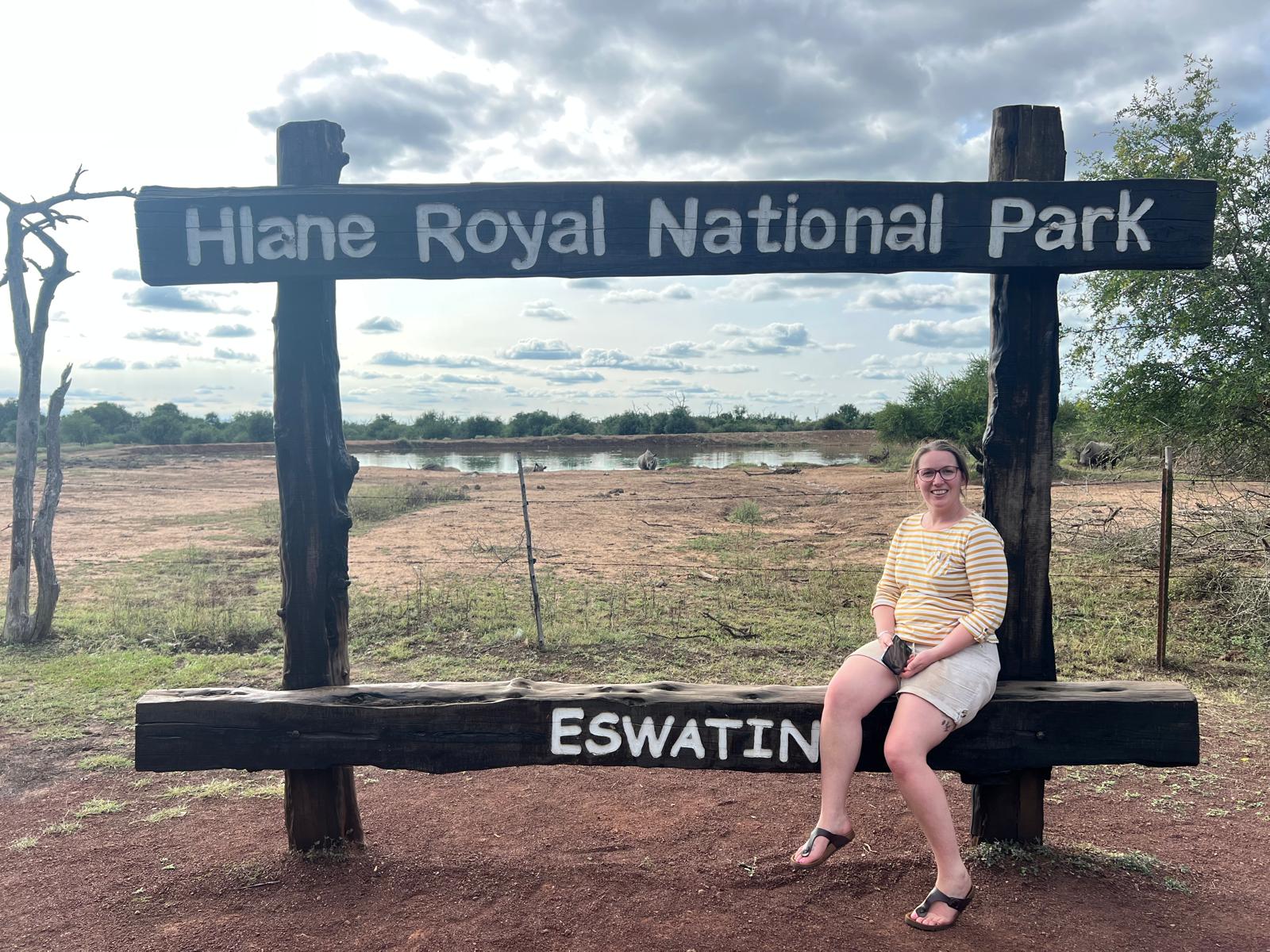 Erica at the Hlane Royal National Park sign in Eswatini