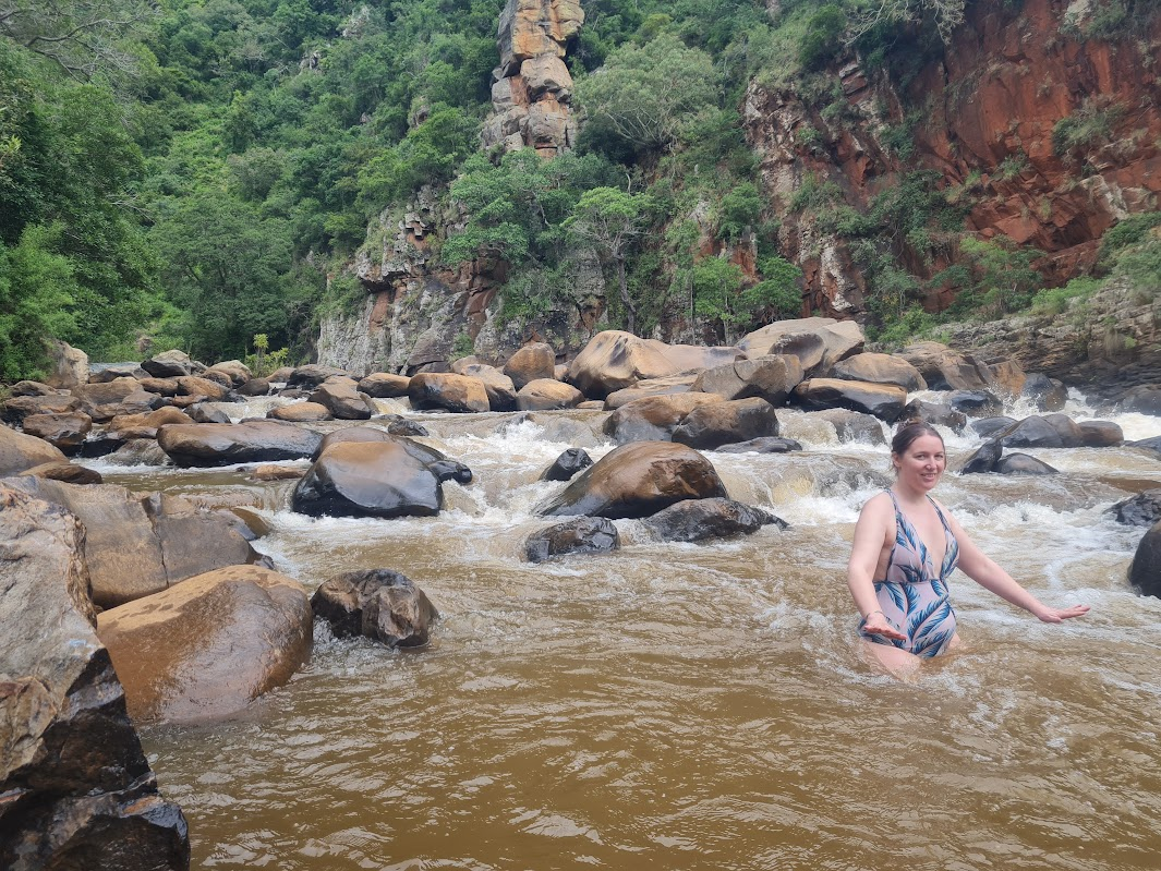 Erica standing in a fast-flowing rocky river below the canyon cliffs