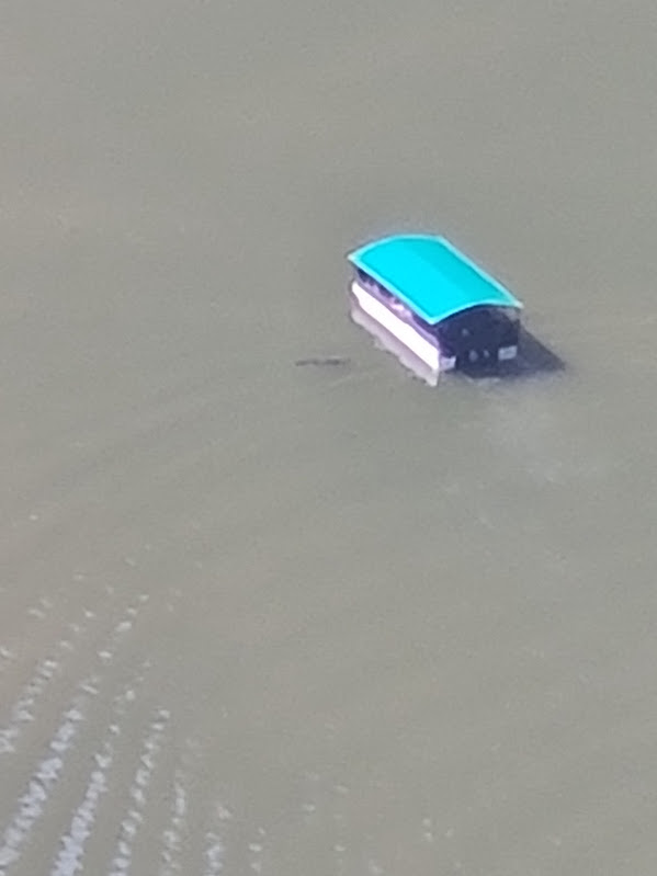 A small boat on the Blyde River seen from high above, beside a dark shape in the water